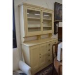 An old pine dresser with a pair of glazed doors enclosing two shelves, on a base with panelled doors