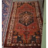 A Persian Hamadan rug with large blue medallion on red ground, decorated with various animal