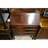 A mahogany crossbanded fall front bureau with fitted interior and three long drawers raised on