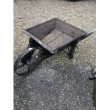 A vintage wooden wheelbarrow with spoked iron wheel