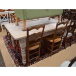 A whitewashed pine kitchen dining table, the rectangular top raised on a plain frieze and turned