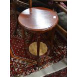 A pair of circular side tables each having turned supports united by a cane worked under tier