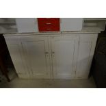 An antique painted pine cabinet with two panelled doors and floral ceramic handles