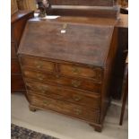 A George III oak fall front bureau on shaped bracket feet