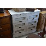 A cream painted chest with two slides and six glass fronted drawers, raised on plinth base