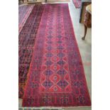 A Persian Baluch runner with two rows of linked diamonds on red ground within guarded repeating