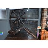 An antique wooden spinning wheel (damaged) to/with another in a dissembled state