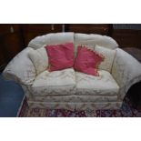 A traditional two seater sofa with cream damask upholstery