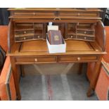 A tropical hardwood roll-top desk with tambour panel enclosing a fitted interior over two frieze