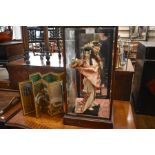 A Japanese Geisha in wood and glazed display case, two miniature Japanese decorative screens and a
