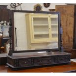 A bevelled oak framed toilet mirror with turned supports on a three drawer platform base with bun