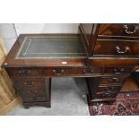 A mahogany twin pedestal desk with gilt tooled green leather top over nine drawers, raised on shaped