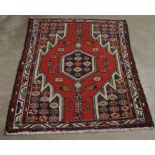 A small Persian Hamadan rug, central navy medallion on red ground, with repeating borders, 125 x