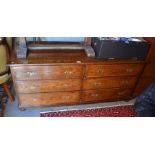 A dark oak low chest of six drawers with brass handles, raised on bun feet