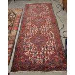 A Persian Hamadan runner, three central lozenge medallions and floral design on cream ground and