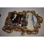 A decorative gilt cartouche-shaped beveled edge wall mirror