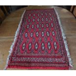 A small Persian Turkoman rug, the repeating gul design on red ground with multi-borders, 127 x 57