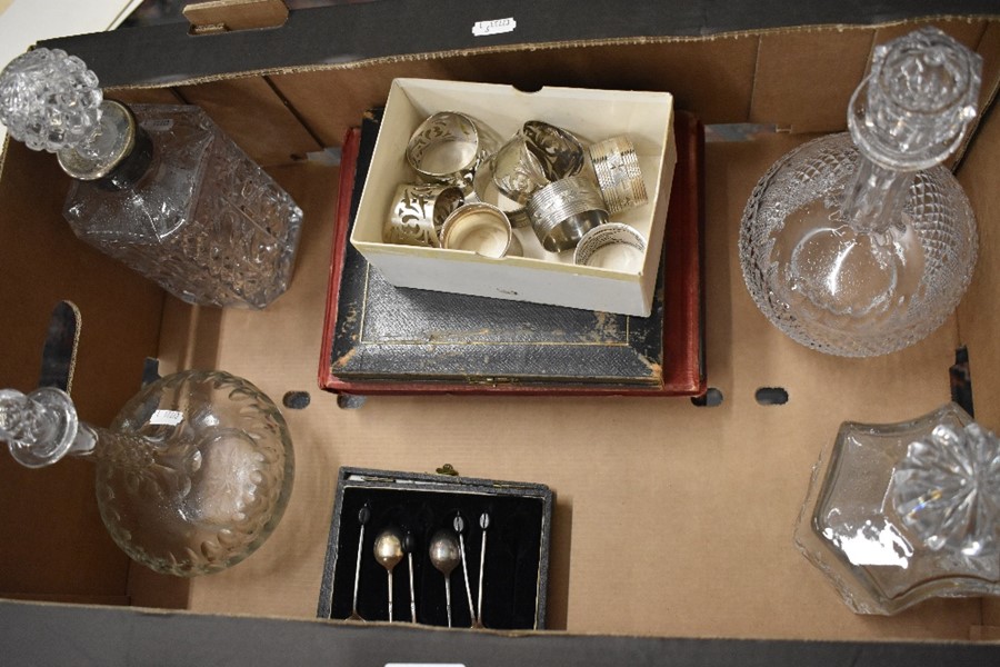 A mixed box to include four glass decanters, collection of napkin ring including a silver example,
