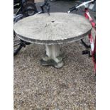 A composite cast stone circular garden table on a shaped quadraform pedestal base