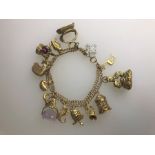 A 9ct yellow gold double curb bracelet with fifteen various charms attached