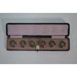 A cased set of six cast and pierced silver buttons