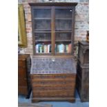 A Georgian oak bureau and associated glazed bookcase to top, all later profusely carved