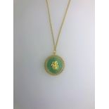 A yellow metal curb chain and pendant with inset green hardstone disk