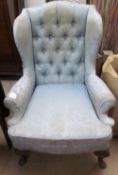 A 19th century wing back chair with a blue damask upholstery on leaf capped cabriole legs