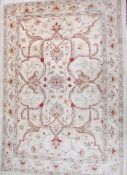 A cream ground rug with scrolling tendrils together with another rug