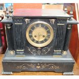 A black slate mantle clock of architectural form with a circular dial with Roman numerals