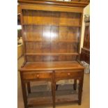 A 20th century oak dresser the moulded cornice above a rack with a planked back and three shelves,