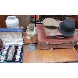 A leather suitcase together with a small case, bowler hat, military cap, cocktail set, pottery vase,