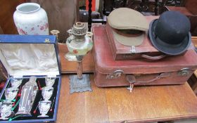 A leather suitcase together with a small case, bowler hat, military cap, cocktail set, pottery vase,