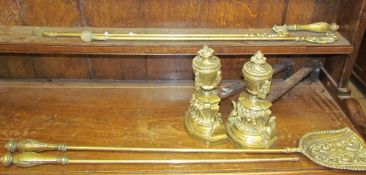 A pair of brass urn shaped fire dogs with brass fire irons