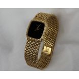 A Lady's 18ct yellow gold Piaget wristwatch, with a black dial and integral bezel and strap,
