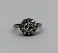 A diamond cluster ring set with a central round brilliant cut diamond approximately 0.