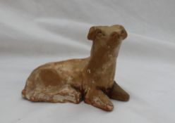 A Chinese pottery dog, laying down with head raised, possibly Yuan dynasty,