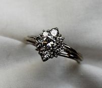 A diamond cluster ring set with a central round brilliant cut diamond approximately 0.