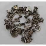 A silver charm bracelet set with numerous charms including a telephone, violin, blackboard, clogs,