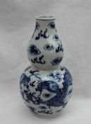 A Chinese porcelain double gourd vase decorated with dragons chasing a pearl, with clouds above,