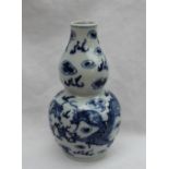 A Chinese porcelain double gourd vase decorated with dragons chasing a pearl, with clouds above,