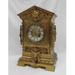 A Gilt metal mantle clock, with a pointed arched top above a cartouche and swags,