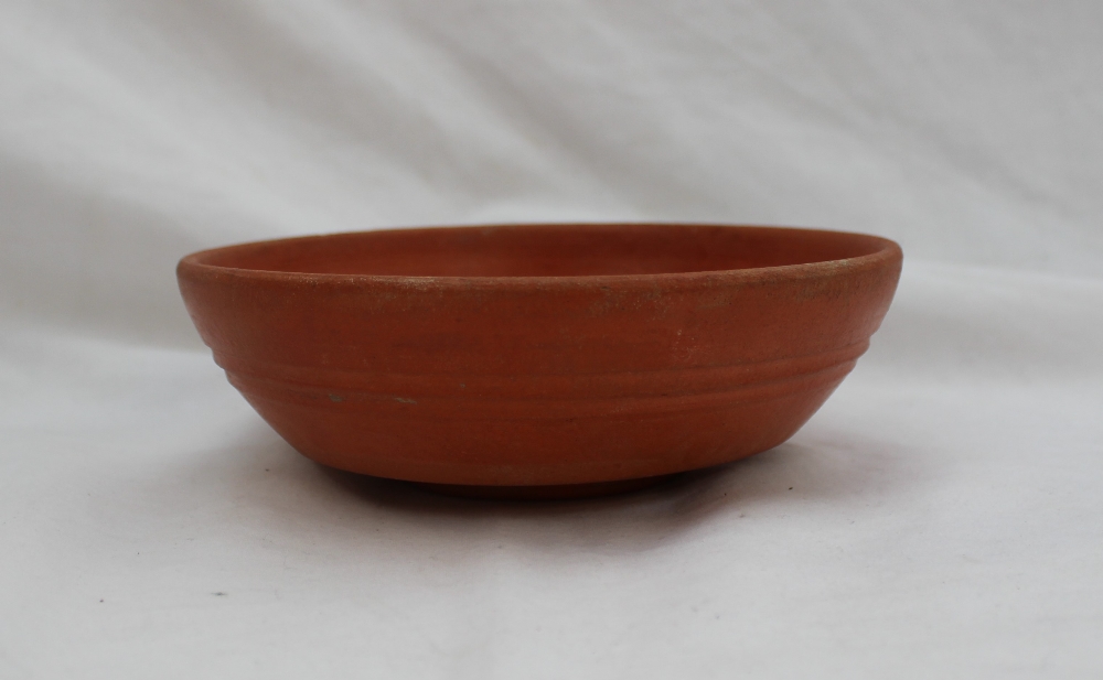 A Roman red ground terracotta bowl, Arretine ware, with a ridged body on a raised foot,