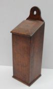 An 18th century oak candle box, with an arched pierced top above a sloping fall and rectangular box,