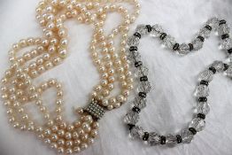 A four strand pearl necklace set with regular pearls to a yellow metal pearl set clasp and another