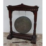 An Edwardian walnut gong stand, with a shaped top and turned columns on a stepped rectangular base,