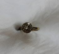 A diamond cluster ring set with a central round brilliant cut diamond approximately 0.