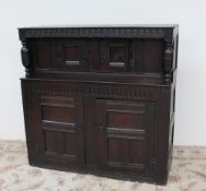 An 18th century oak court cupboard, the planked top above a carved frieze and turned columns,