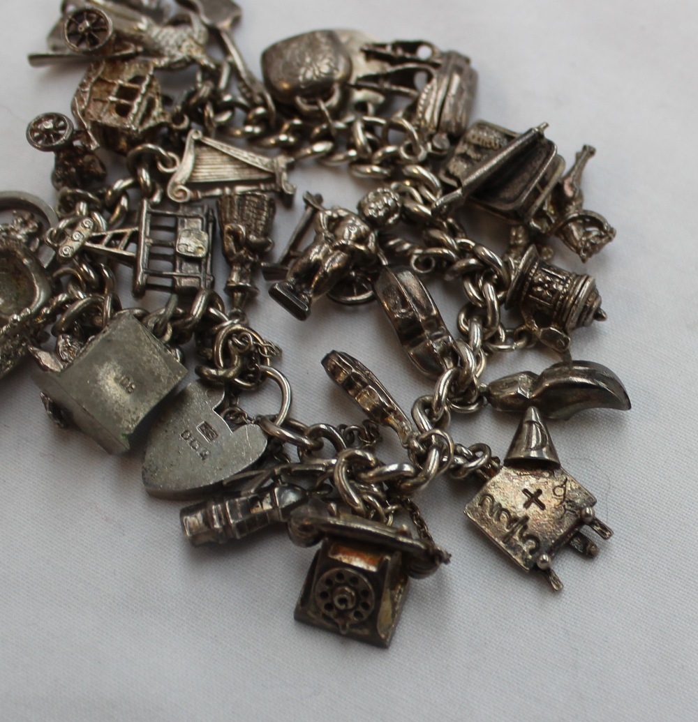 A silver charm bracelet set with numerous charms including a telephone, violin, blackboard, clogs, - Image 2 of 2