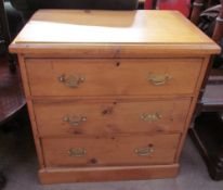 A small pine chest with a rectangular top and three drawers on a plinth base